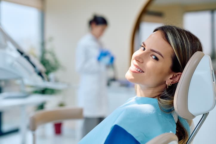 Smiling woman relaxing in a dental chair after treatment, representing comfortable professional dental care and confidence in her smile.