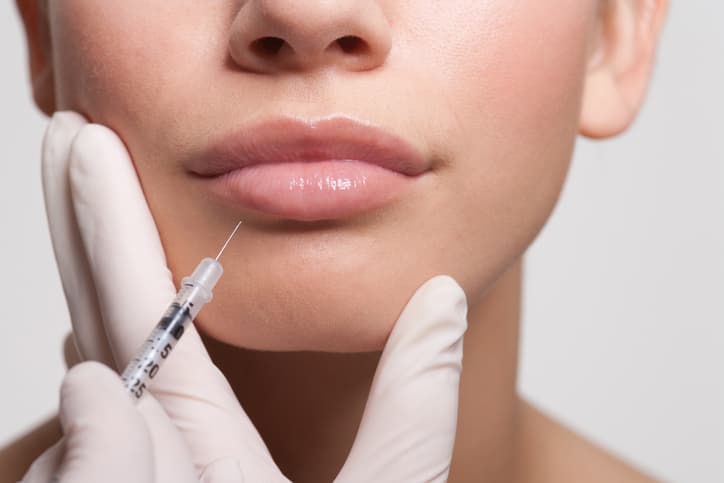 Cosmetic injectable treatment being administered near a woman’s lips
