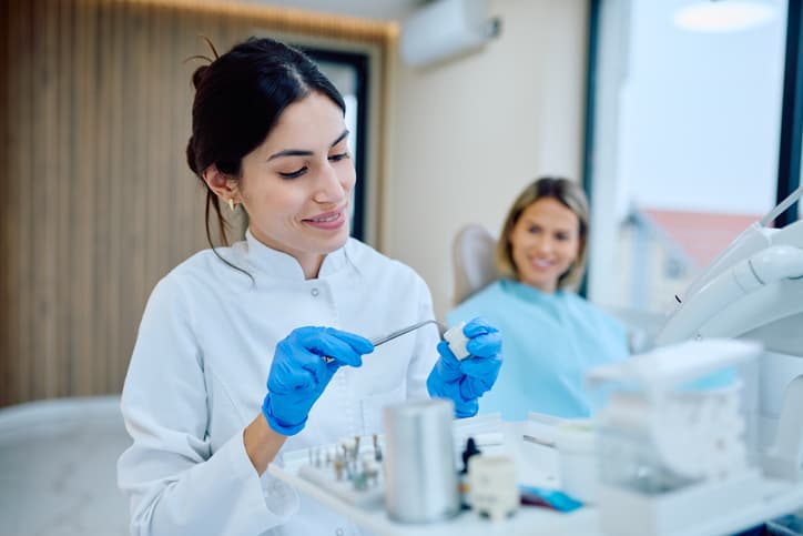 Dental professional preparing instruments while a patient waits in the treatment room